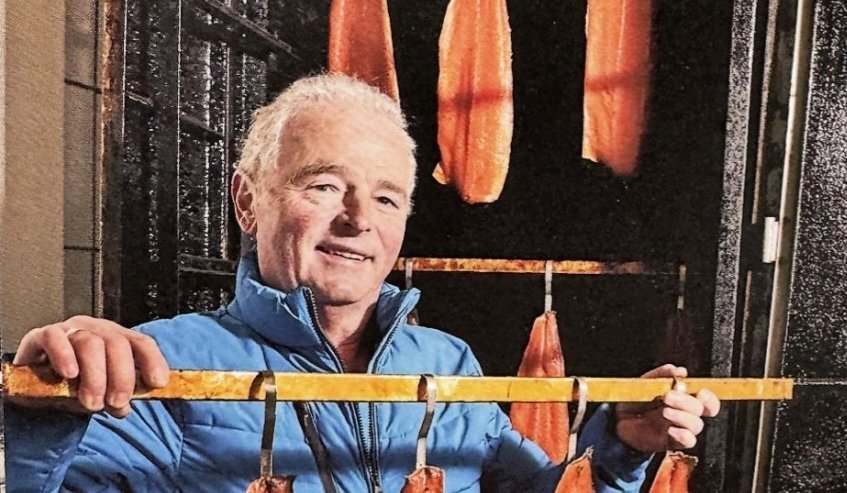 Richard Huth von der Räucherei Salmore hängt den frisch geräucherten Lachs ab.